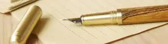 Close-up picture of a fountain pen and letter paper, symbolizing the act of writing to someone to get in contact with them in formal fashion.